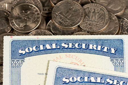 USA Social security cards laid on pile of quarter coins to illustrate money in retirementの写真素材