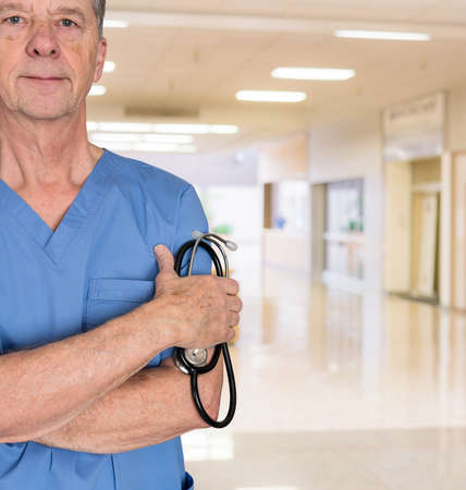 Senior doctor or medical specialist in blue scrubs and welcoming the patient to a hospitalの写真素材