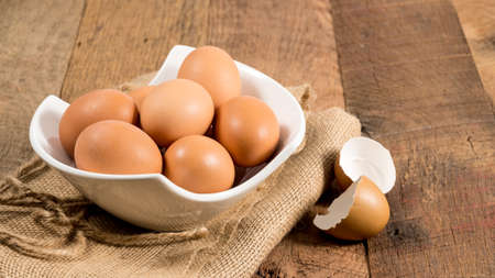 Easter background with brown organic eggs arranged in a bowl on burlap sack on rustic wooden table