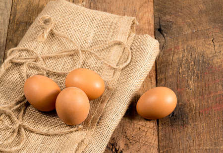 Easter background with brown organic eggs arranged on burlap sack on rustic wooden tableの写真素材