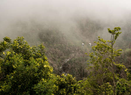 Cable cars in the mist up the mountain from Monte to Botanical Gardens in Madieraの写真素材
