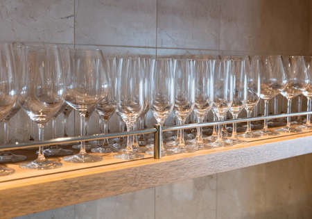Shelf of wineglasses of difference shapes in bar or restaurantの写真素材