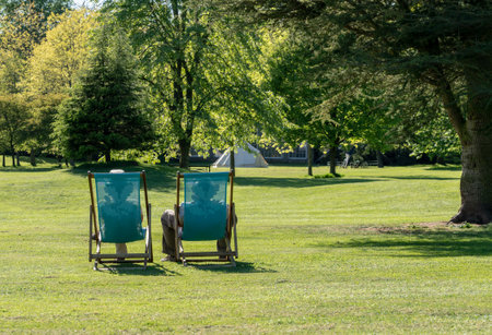 STOKE ON TRENT, UK - MAY 14, 2018: Couple relaxing in lawn deckchairs in typical english settingのeditorial素材