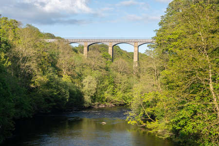 Spring trees frame the old Pontcysyllte Aqueduct near Chirk carrying Llangollen Canal across river Deeの写真素材