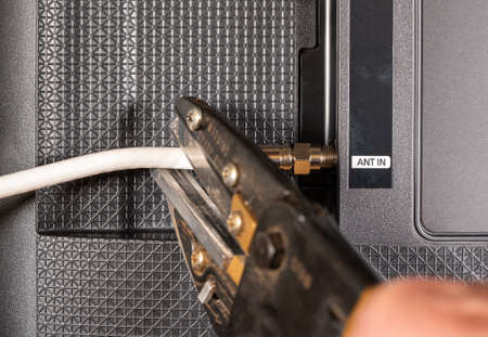 Close up of senior caucasian man hand cutting the aerial connection to his TV to illustrate cutting...