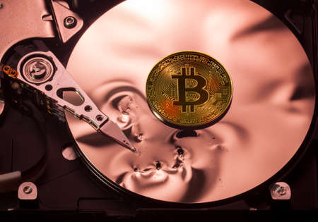 Bitcoin superimposed on the damaged discs of a hard drive storage to illustrate bitcoin market crashの写真素材