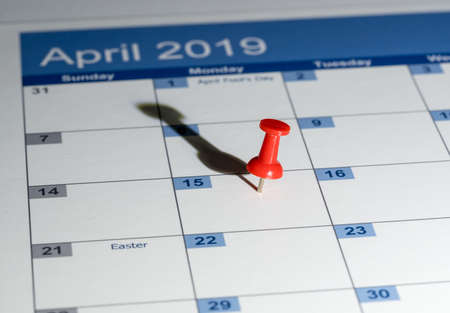 Tax day is April 15th for filing to IRS with red push pin in calendar for reminder