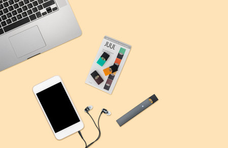 MORGANTOWN, WV - 25 AUGUST 2018: Juul e-cigarette or nicotine vapor dispenser box on desktop with phone and laptopのeditorial素材