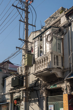 SHANGHAI, CHINA - 26 OCTOBER 2018: Tangle of electric and telephone wires on pole in front of buildingのeditorial素材