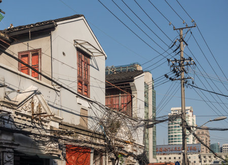 SHANGHAI, CHINA - 26 OCTOBER 2018: Tangle of electric and telephone wires on pole in front of buildingのeditorial素材