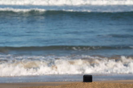 Focus on camera taking video or timelapse footage from sandy beach towards rolling surf and wavesの写真素材