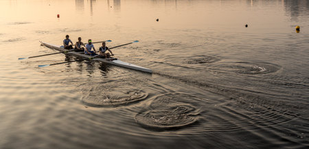 LONDON, UK - 17 APRIL 2019: Sunrise lights up team of four rowers in canoe practicing in London Docklandsのeditorial素材