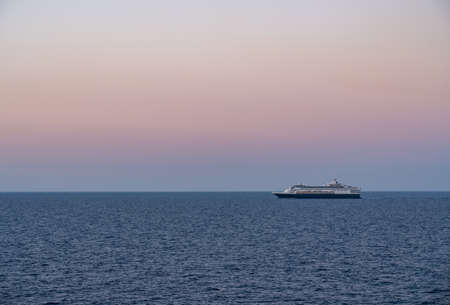 Small cruise liner sailing across the ocean as dawn starts to light the skyの写真素材