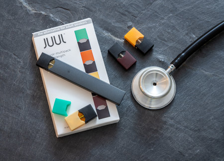 MORGANTOWN, WV - 26 AUGUST 2019: Juul e-cigarette or nicotine vapor dispenser box on slate with stethoscopeのeditorial素材