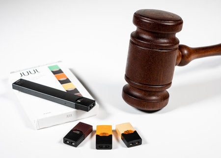 MORGANTOWN, WV - 29 AUGUST 2019: Juul e-cigarette or nicotine vapor dispenser box with Judges gavel for lawsuitのeditorial素材