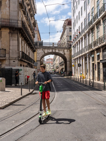 Lisbon, Portugal - 9 August 2019: Young man riding a Lime S electric scooter along narrow streets of Lisboaのeditorial素材