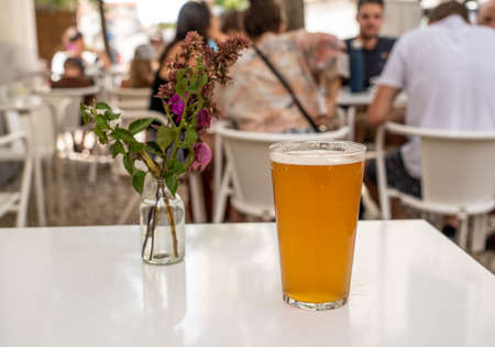 Focus on a cold glass of IPA beer with decorative flowers on white table in Lisbon bistroの写真素材