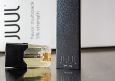 Morgantown, WV - 10 September 2019: Juul e-cigarette and nicotine vaping container on metal table