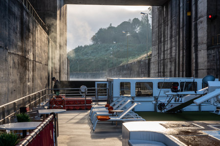 Porto, Portugal - August 13, 2019: Sailor watches the sides of river cruise boat inside the lock at...