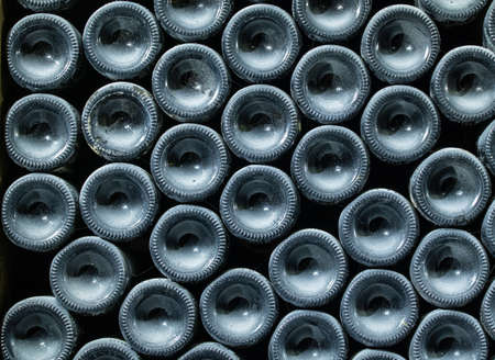 Stacks of wine bottles laying flat in wooden racks in old wine cellar or caveの写真素材