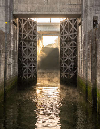 Solid wooden lock gates opening to show the mist from sunrise at the Crestuma Lever dam on River Douro in Portugalの写真素材
