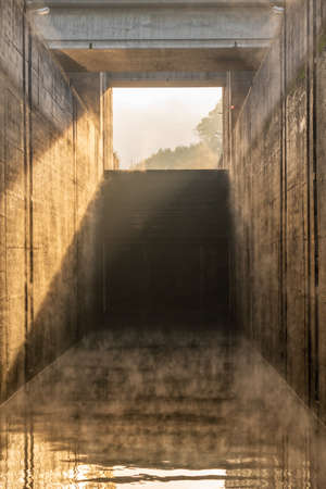 Calm water inside the concrete lock with the mist from sunrise at the Crestuma Lever dam on River Douro in Portugalの写真素材