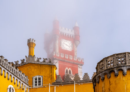 Sintra, Portugal - 21 August 2019: Low clouds and mist hide the colorful and dramatic towers of Pena...