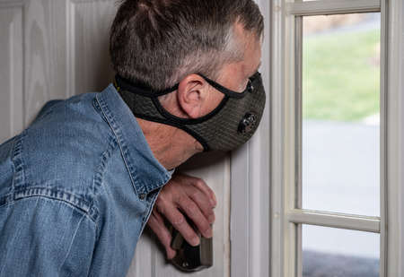 Concerned and worried man wearing a protective breathing mask against flu and looking out of front...