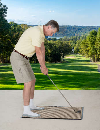 Senior caucasian man practicing his golf grip and swing on a mat in bedroom at home and imagining he was outside on a real golf courseの写真素材