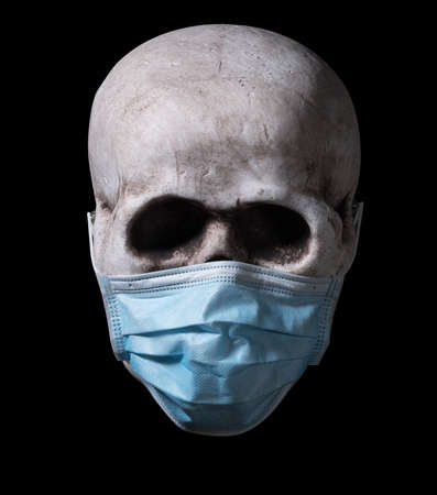 Human skull with a medical face mask isolated on blackの写真素材