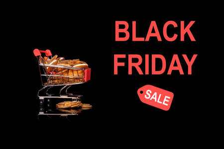 Mockup or background advert for Black Friday with shopping cart filled with gold coins to illustrate savings to be found in the salesの写真素材