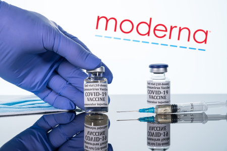 Morgantown, WV - 16 December 2020: Small bottle of coronavirus vaccine with syringe with background of Moderna logoのeditorial素材