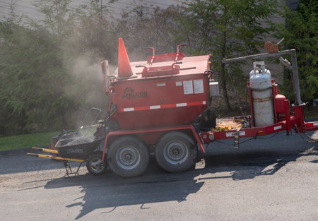 Morgantown, WV - 7 April 2021: Workers applying a layer of tarmac or extra blacktop to repair damage...