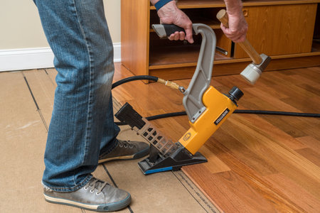 Morgantown, WV - 7 June 2021: Installer activating Bostitch nailing gun to install Brazilian Cherry tropical hardwood flooringのeditorial素材