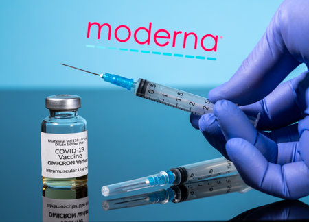 Morgantown, WV - 7 December 2021: Small bottle of coronavirus vaccine for Omicron variant with syringe with background of Moderna logoのeditorial素材