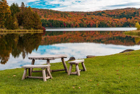 Rustic wooden table and chairs by Silver Lake in Barnard Vermont during the fall seasonの写真素材