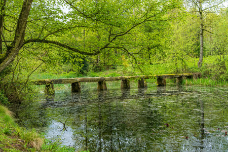 Old stone slab granite bridge across a pond or calm lake in English park landの写真素材