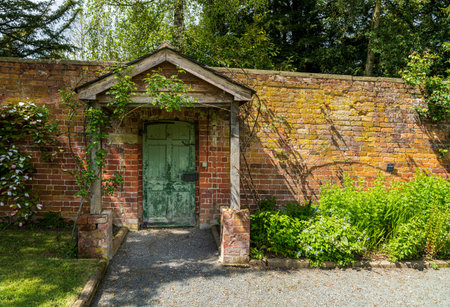 Painted green door and wooden porch as entrance to walled garden made with brickの写真素材