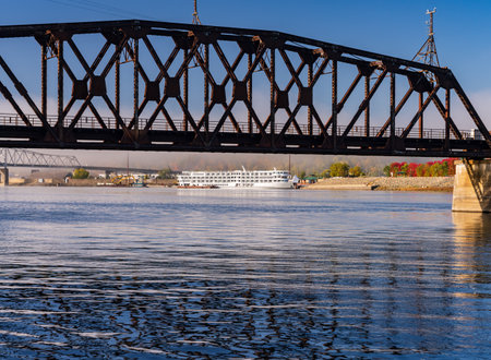 Dubuque Railroad bridge across Upper Mississippi on calm misty morning with docked river cruise boatの写真素材