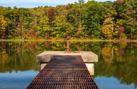 Changing leaves in autumn with metal walkway and platform in calm reservoir in Coopers Rock State Forest near Morgantown, WVの写真素材