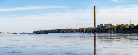 Large barges pass in front of New Madrid power station in Missouri on the Mississippi river in broad panoramaの写真素材