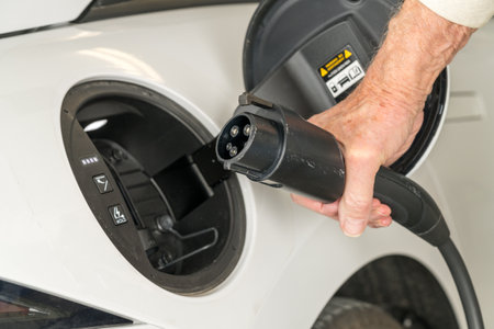 Level 2 240V home charging with J1772 plug being inserted into the port of modern electric car to...