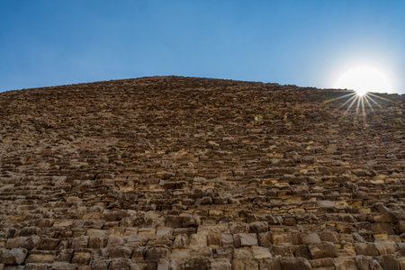 Sun flare over the top edge of the rough stone surface of the Great Pyramid of Gizaの写真素材