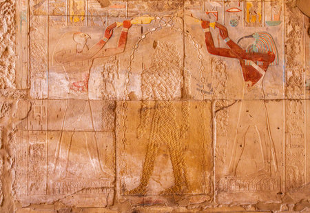 Detailed carvings showcase ancient religious rituals in Karnak, with the central figure disfigured by early christiansの写真素材