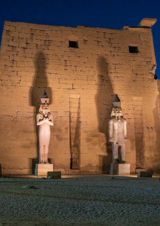 Massive numerous stone columns supporting roof with statues in Luxor Temple in Egypt illuminated at nightの写真素材
