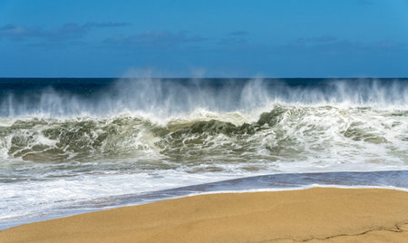 Ocean waves crashing on the sandy beach with the turquoise water rippling and splashing.の写真素材