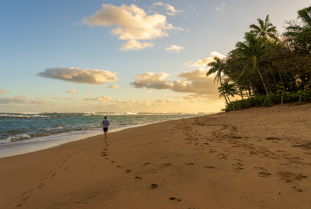 Running on Tunnels Beach at dawn on the island of Kauai, Hawaii on a calm winter morningの写真素材