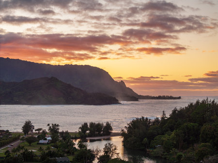 A vibrant aerial view of sunset clouds over the lush landscape of Hanalei Bay, framed by majestic mountains in Kauai, Hawaii.の写真素材