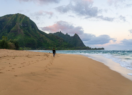 Walker on Tunnels Beach at dawn on the island of Kauai, Hawaii on a calm winter morningの写真素材