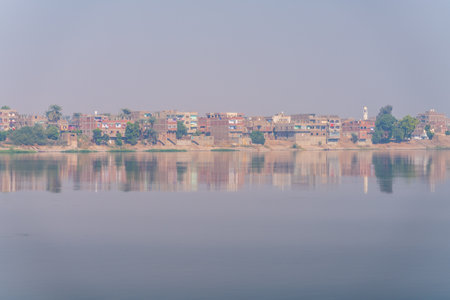 Small city of AZ Zawayah in Qena Governate of Egypt by side of Nile River with misty heat haze over the riverの写真素材